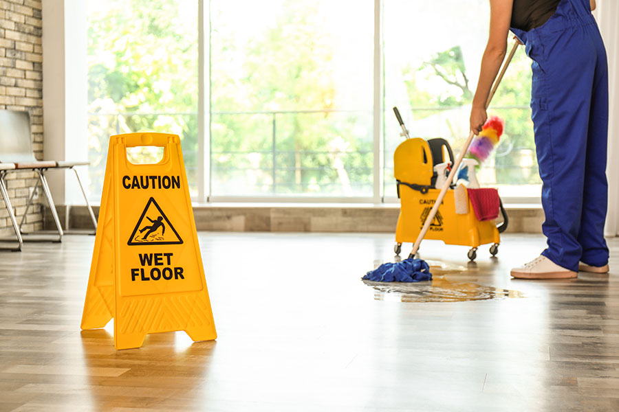 A professional janitorial service in St Charles, MO that is using a mop to clean the hardwood floors in an office setting.