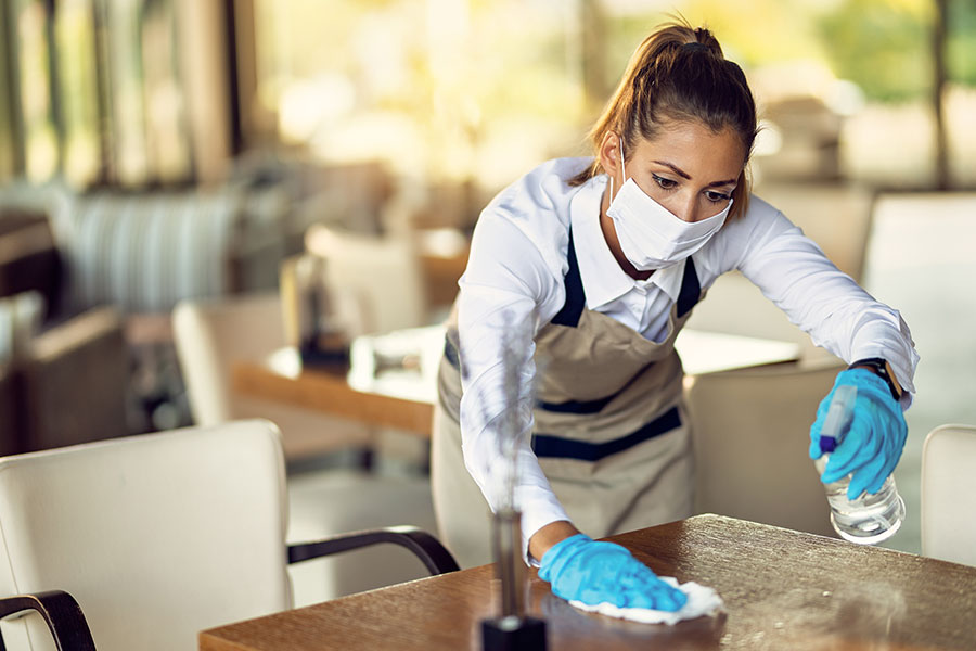 A professional maid using eco-friendly cleaning solutions to clean a table in a commercial business in St. Charles, MO for seasonal cleaning.
